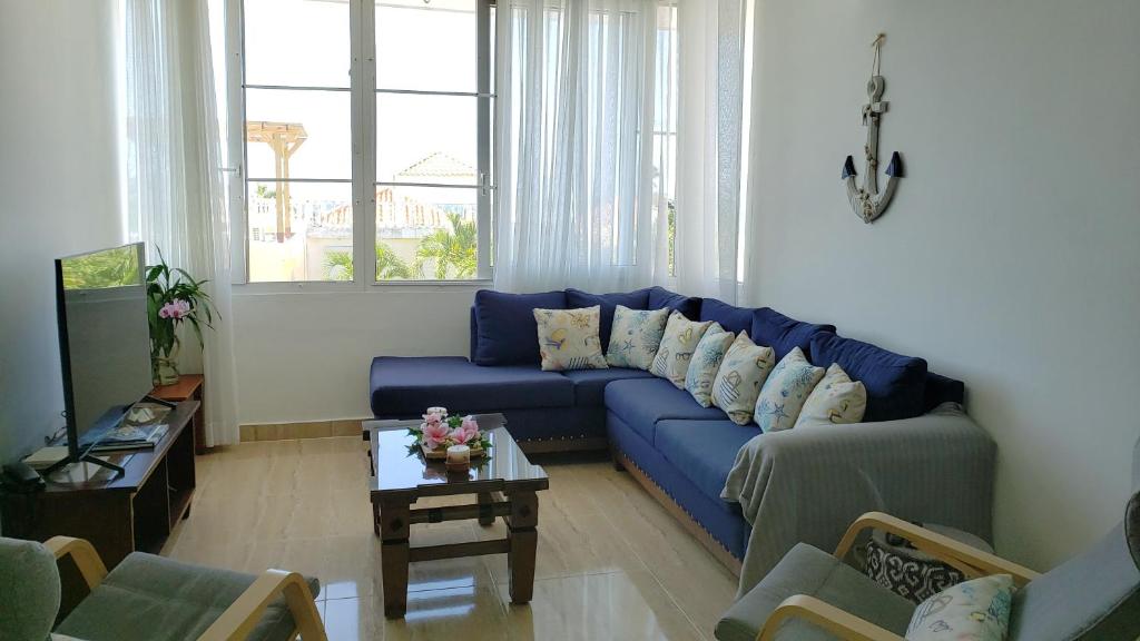 - un salon avec un canapé bleu et une table dans l'établissement Juan Dolio - Hermoso y acogedor apartamento, à Juan Pedro