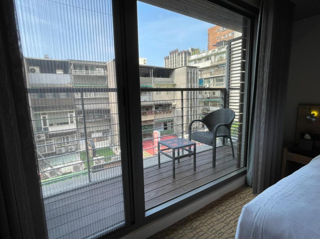 a bedroom with a balcony with a table and a chair at Simple + Hotel in Taipei