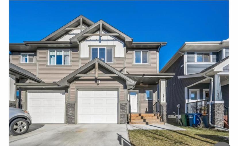 a house with two garage doors in a driveway at Beautiful and Spacious 1 room in a very quiet area in Airdrie