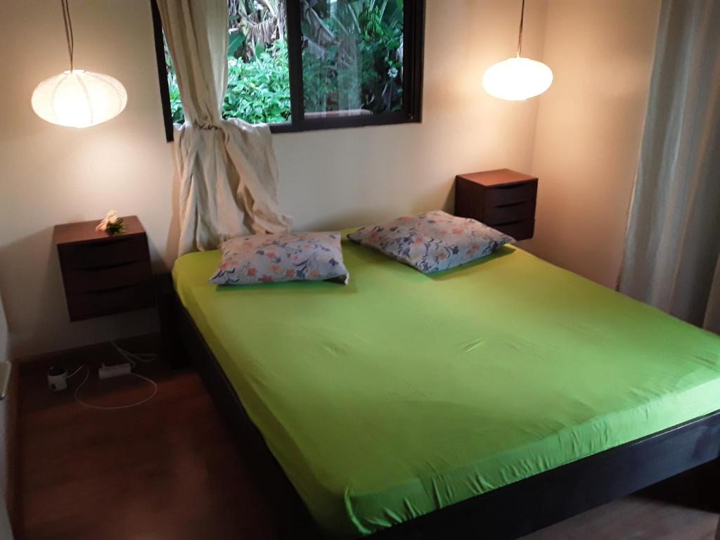 um quarto com uma cama verde e 2 almofadas em ROYAL VAI em Faaa