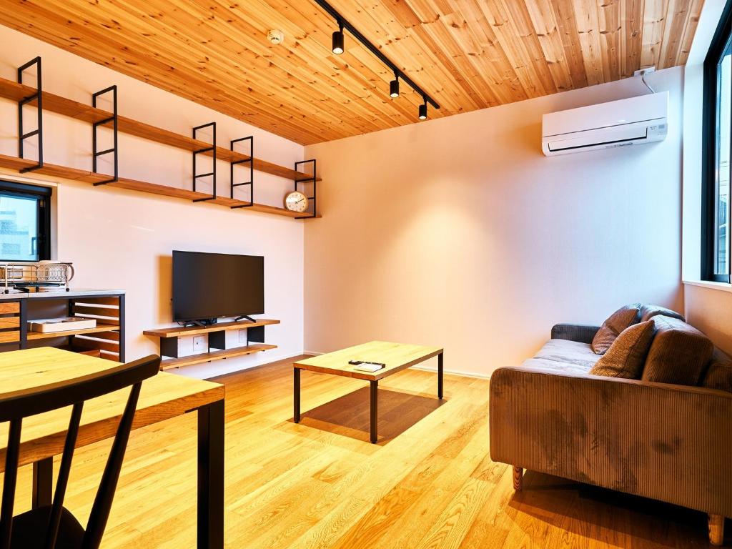 Rakuten STAY HOUSE x WILL STYLE Miyazaki Aoshima 101 في ميازاكي: غرفة معيشة مع أريكة وتلفزيون