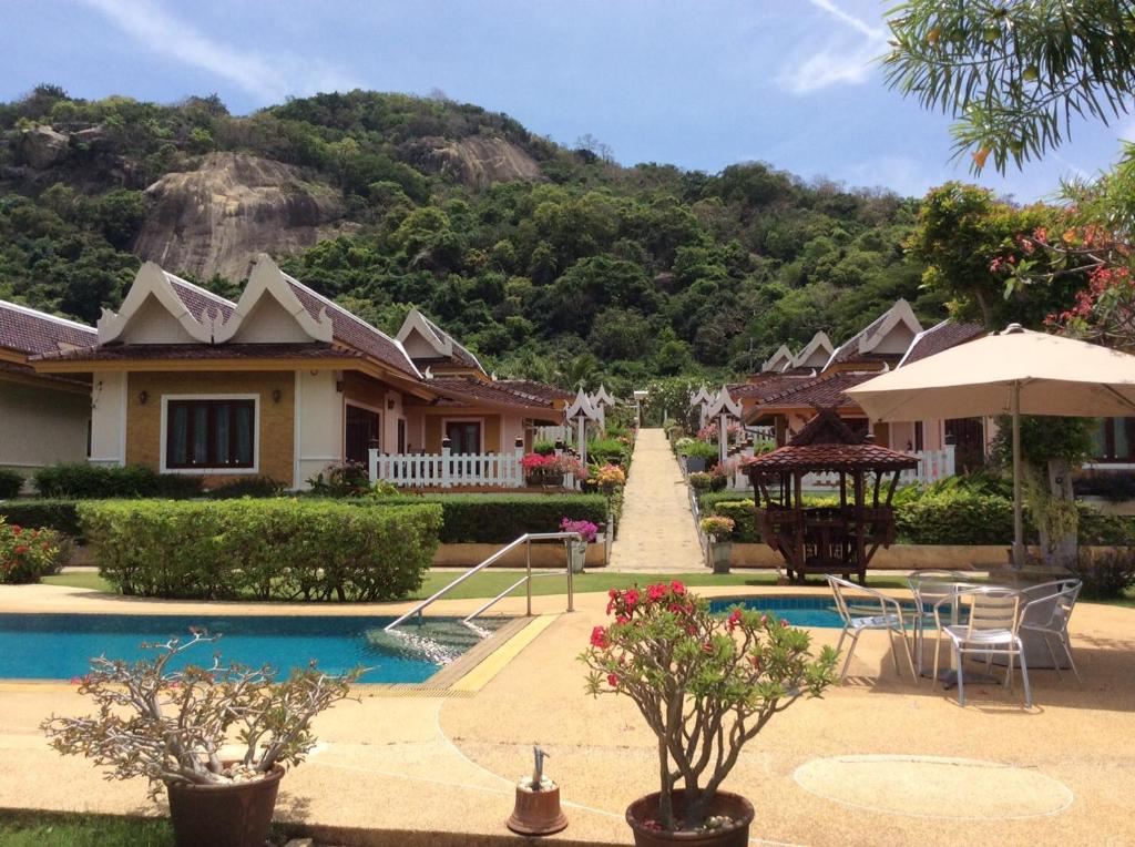 a resort with a swimming pool with a mountain in the background at Khao Tao lake & beach villas, Hua Hin. in Khao Tao