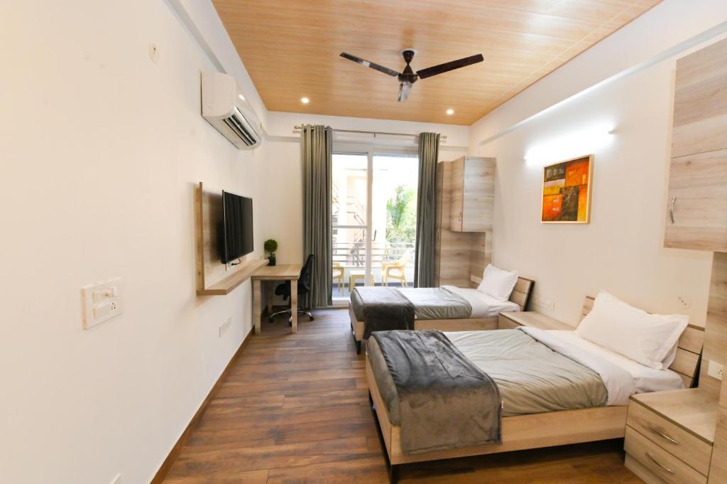 sala de estar con 2 camas y TV en Stay Studio Hotel & Residences, en Gurgaon