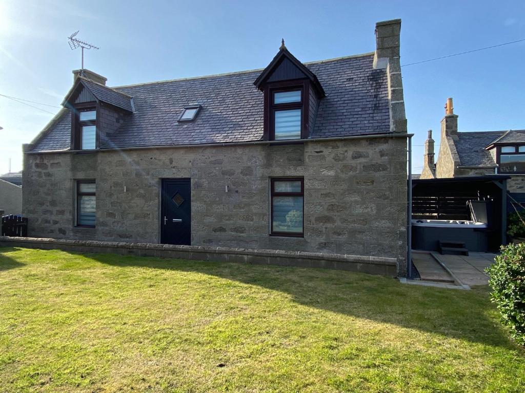 a stone house with a large yard in front of it at Fisherman's Cottage in Fraserburgh