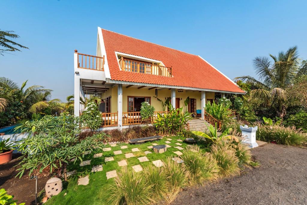 una casa con un jardín delante de ella en SaffronStays Happy Fields, Pune - luxury farmstay with farm to table food en Pune