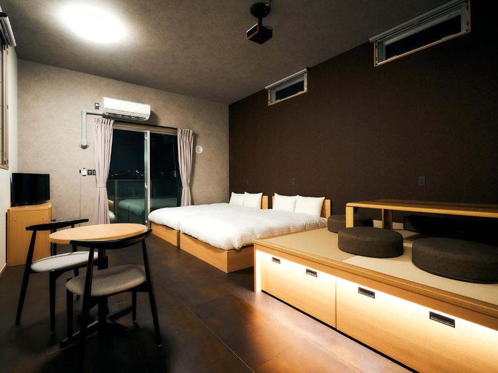 ein Schlafzimmer mit einem Bett, einem Tisch, einem Bett und einem Schreibtisch in der Unterkunft Rakuten STAY Hakata Gion 502 Deluxe Room in Fukuoka