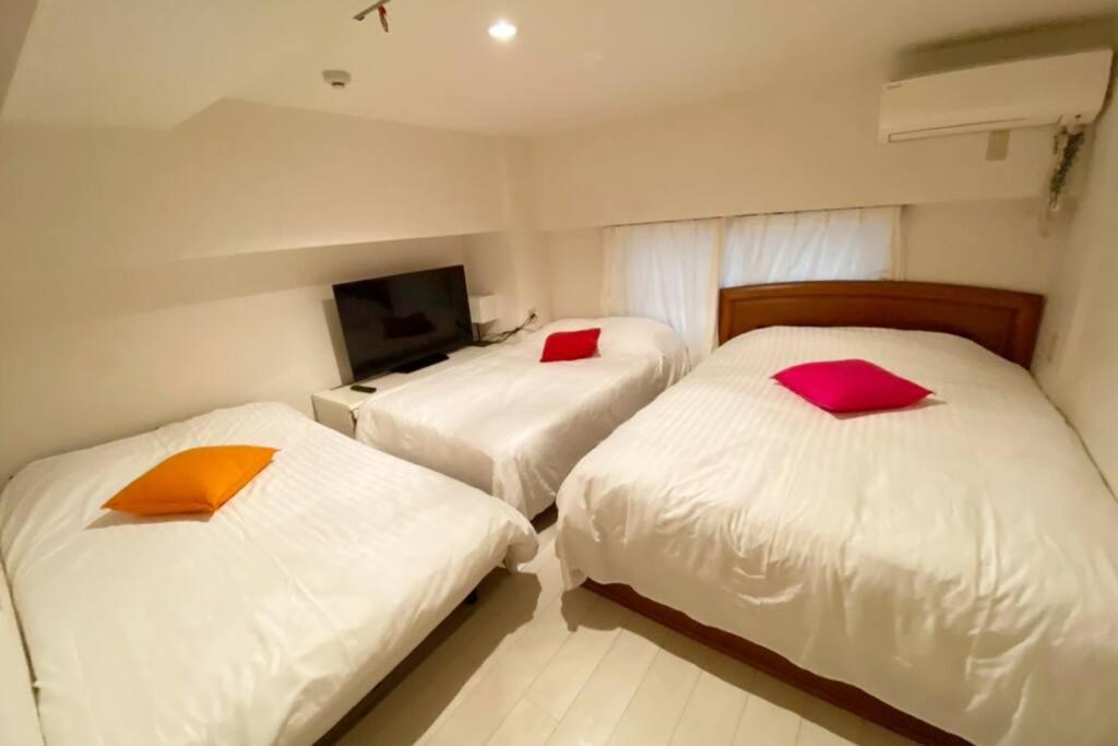2 camas con almohadas rojas y naranjas en una habitación en Takemura Building106, en Tokio