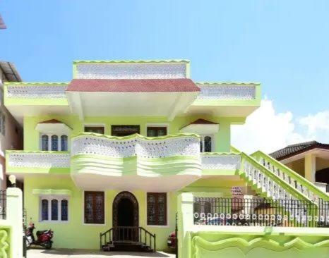 a large yellow building with a balcony on it at Long Wood Hills Cottage in Ooty