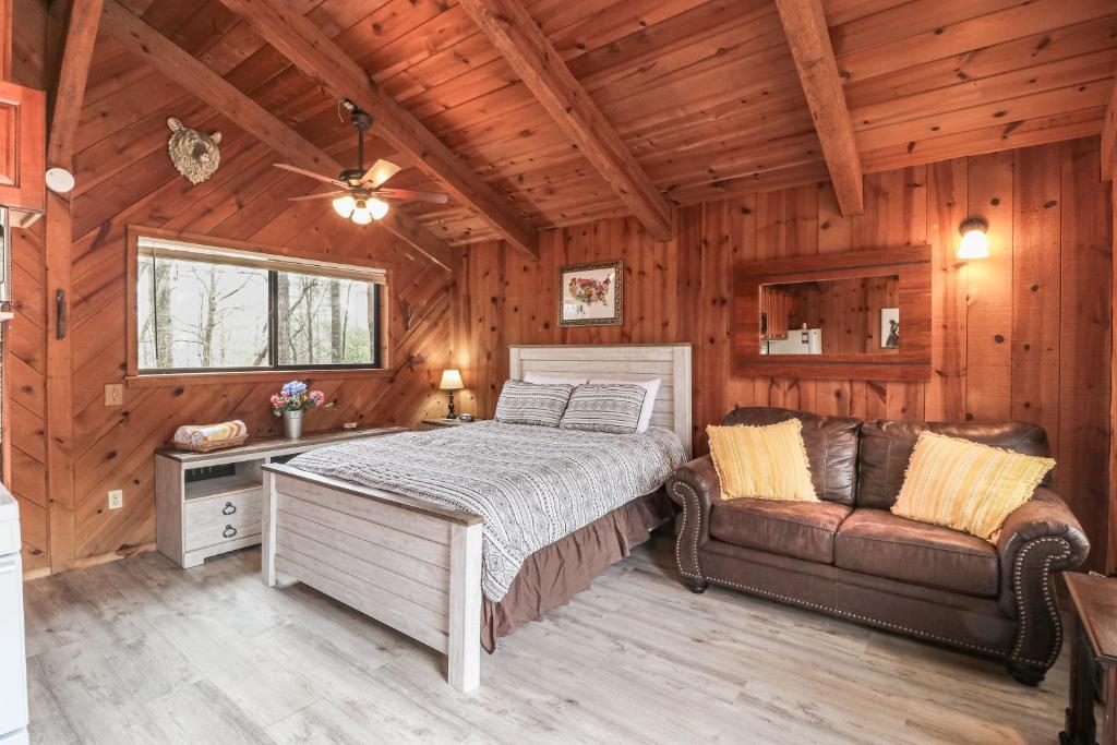 a bedroom with a bed and a couch in a cabin at Azalea Pine Bungalow in Sautee Nacoochee