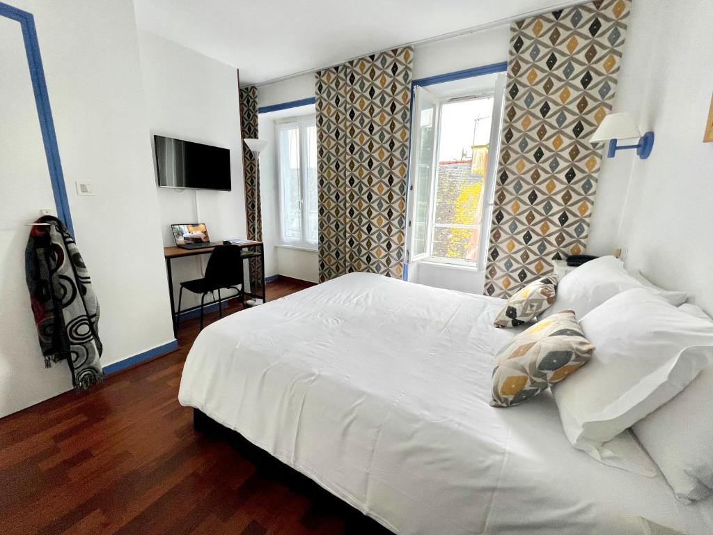 een slaapkamer met een groot wit bed en een bureau bij L'Hôtel de Loctudy in Loctudy