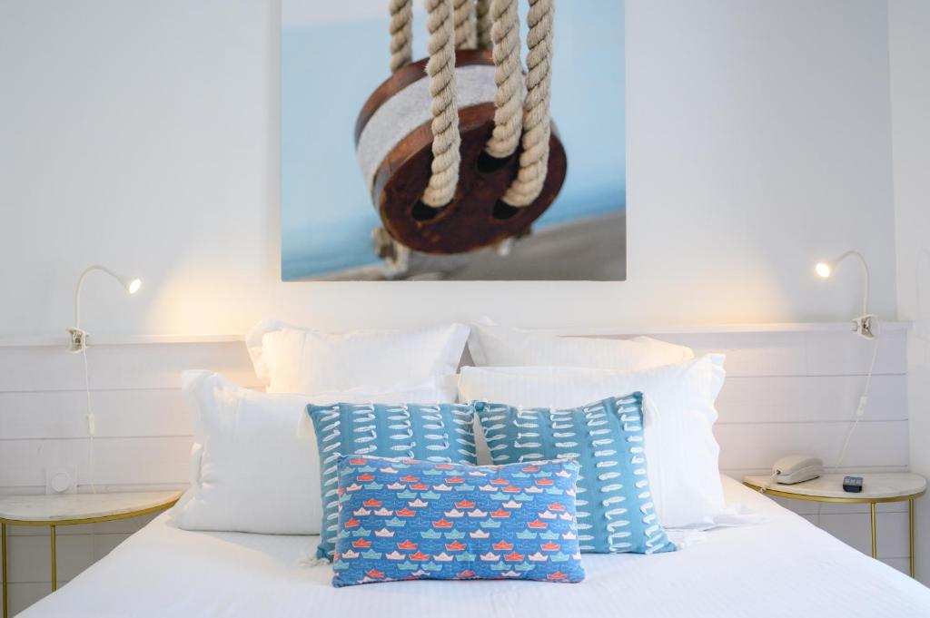 a bed with white pillows and a picture on the wall at Hôtel La Jetée in Saint-Martin-de-Ré