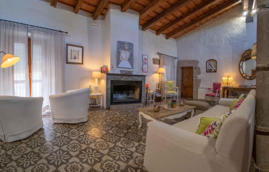 Elle comprend un salon doté d'un mobilier blanc et d'une cheminée. dans l'établissement Can Bayre-Casa Rural, à Fortiá