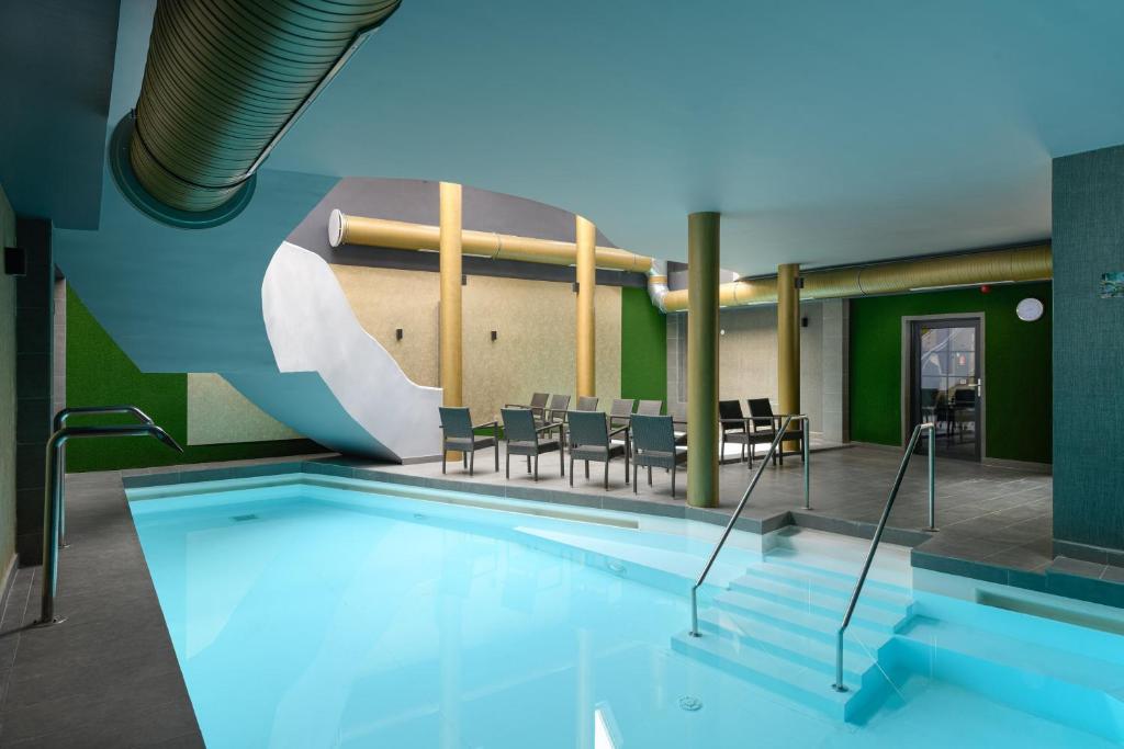 a large swimming pool with chairs and a table at Park Hotel Ambrózia in Hajdúszoboszló