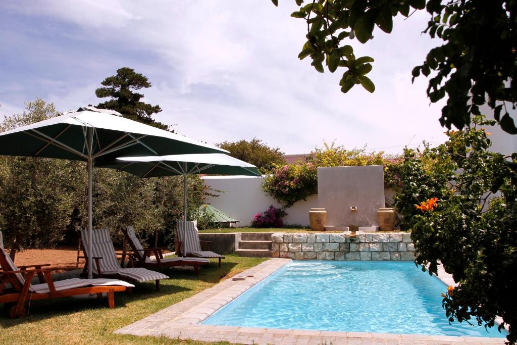 a swimming pool with two chairs and an umbrella at De Doornkraal Vinotel in Riversdale
