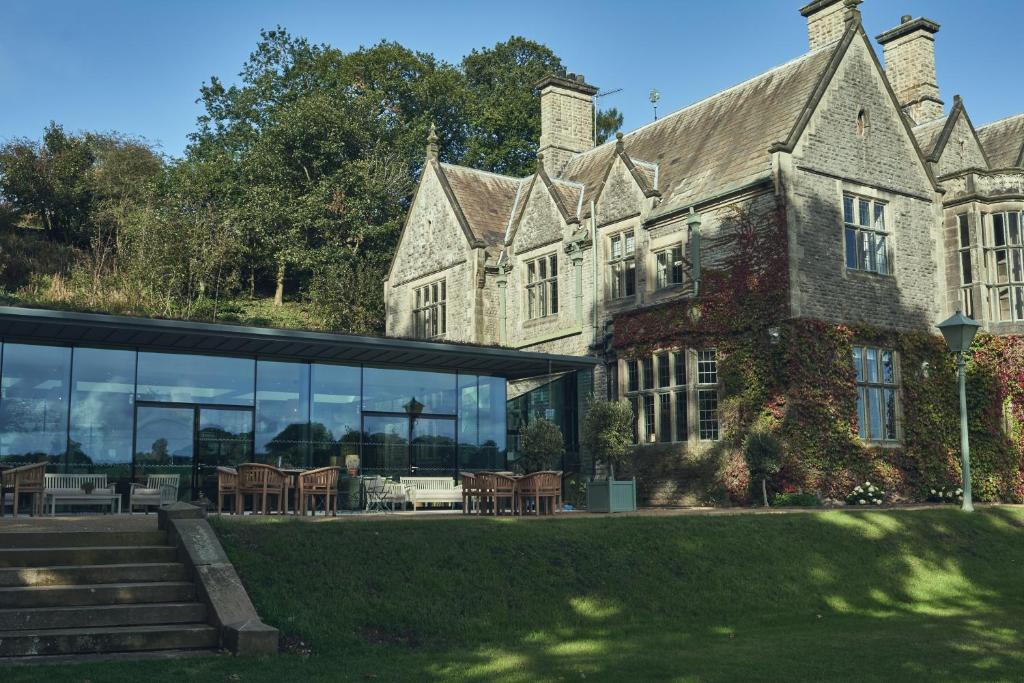 a large stone building with glass windows and tables at Wildhive Callow Hall in Ashbourne