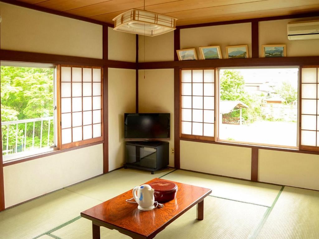 Cette chambre dispose d'une table, d'une télévision et de fenêtres. dans l'établissement Maruyaso, à Fujikawaguchiko