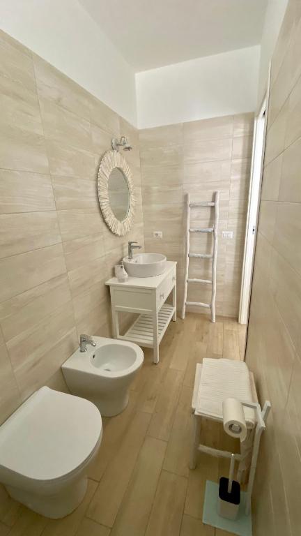 łazienka z 2 toaletami, umywalką i lustrem w obiekcie Casa Perla w mieście Favignana