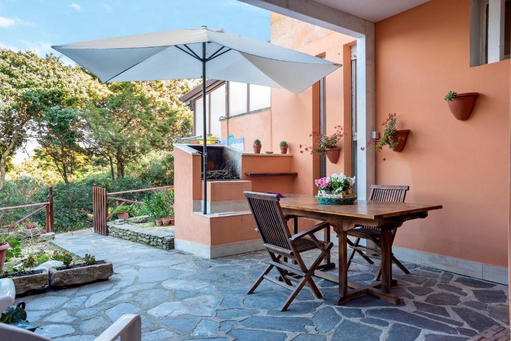 einen Holztisch mit Sonnenschirm auf einer Terrasse in der Unterkunft Casa Erica in Stintino