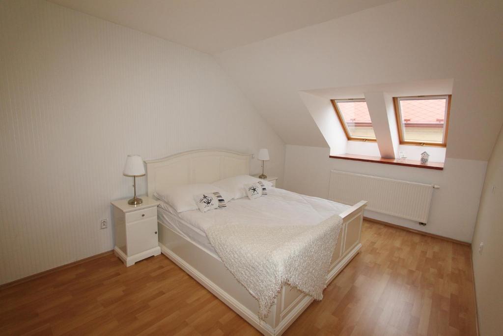1 dormitorio con 1 cama blanca y 2 ventanas en Apartmán U krále - 3, en Jičín