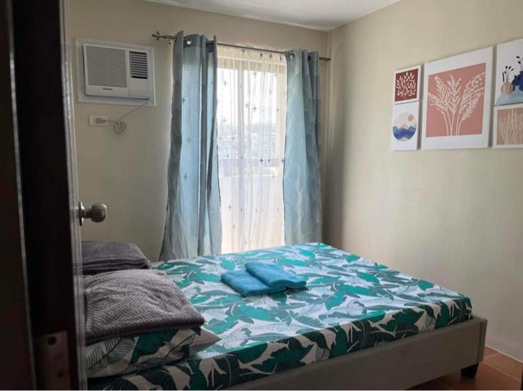ein kleines Schlafzimmer mit einem Bett und einem Fenster in der Unterkunft Qs and YPJs 2BR Condo One Oasis Cagayan de Oro in Cagayan de Oro