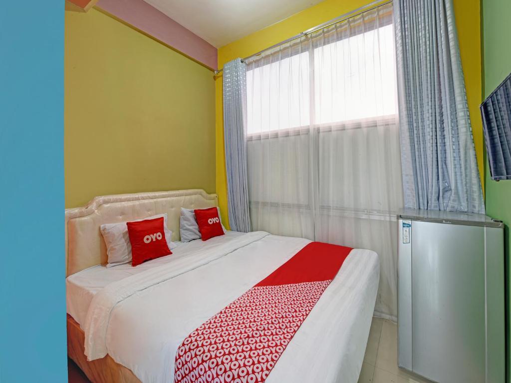 a bedroom with a bed with red pillows and a window at OYO 90451 Hotel Roda Mas 1 in Purwokerto