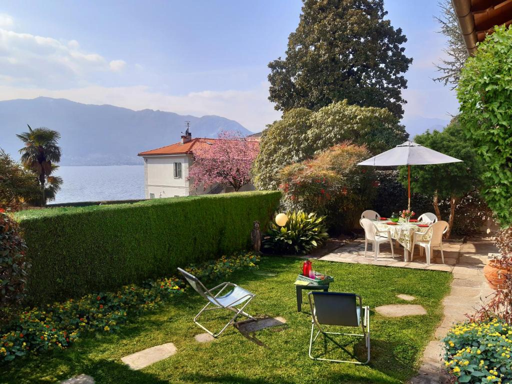 - un jardin avec une table, des chaises et un parasol dans l'établissement Villino Alborella, à Verbania