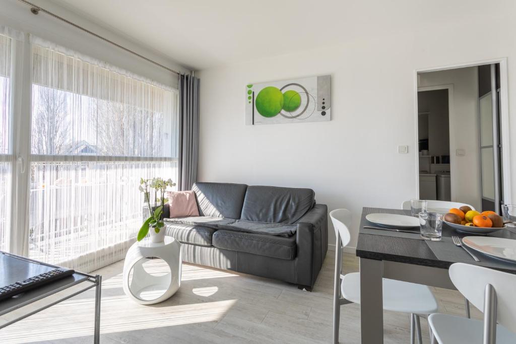a living room with a couch and a table at Le P'tit Idéal in Cabourg