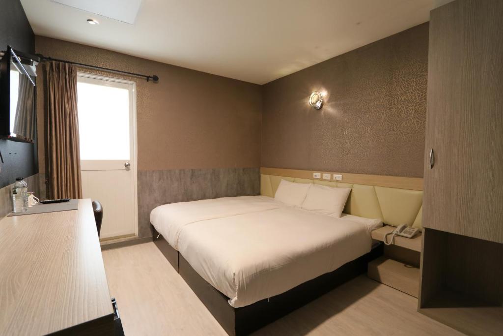 a small bedroom with a bed and a window at Chao She Hotel in Kaohsiung