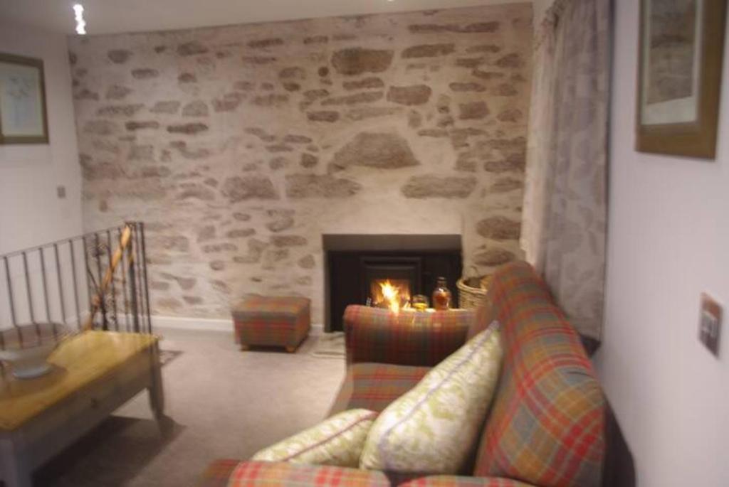 sala de estar con sofá y chimenea en Taymount Cottage, en Caputh