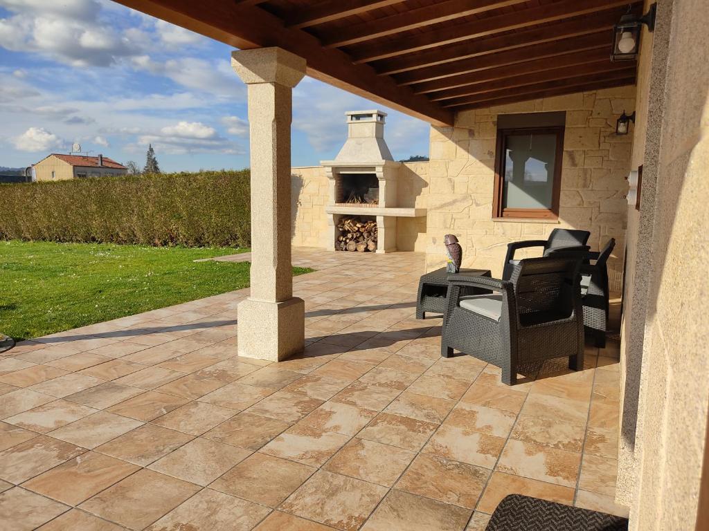an outdoor patio with chairs and a fireplace at A Chamiseiriña in Padrón