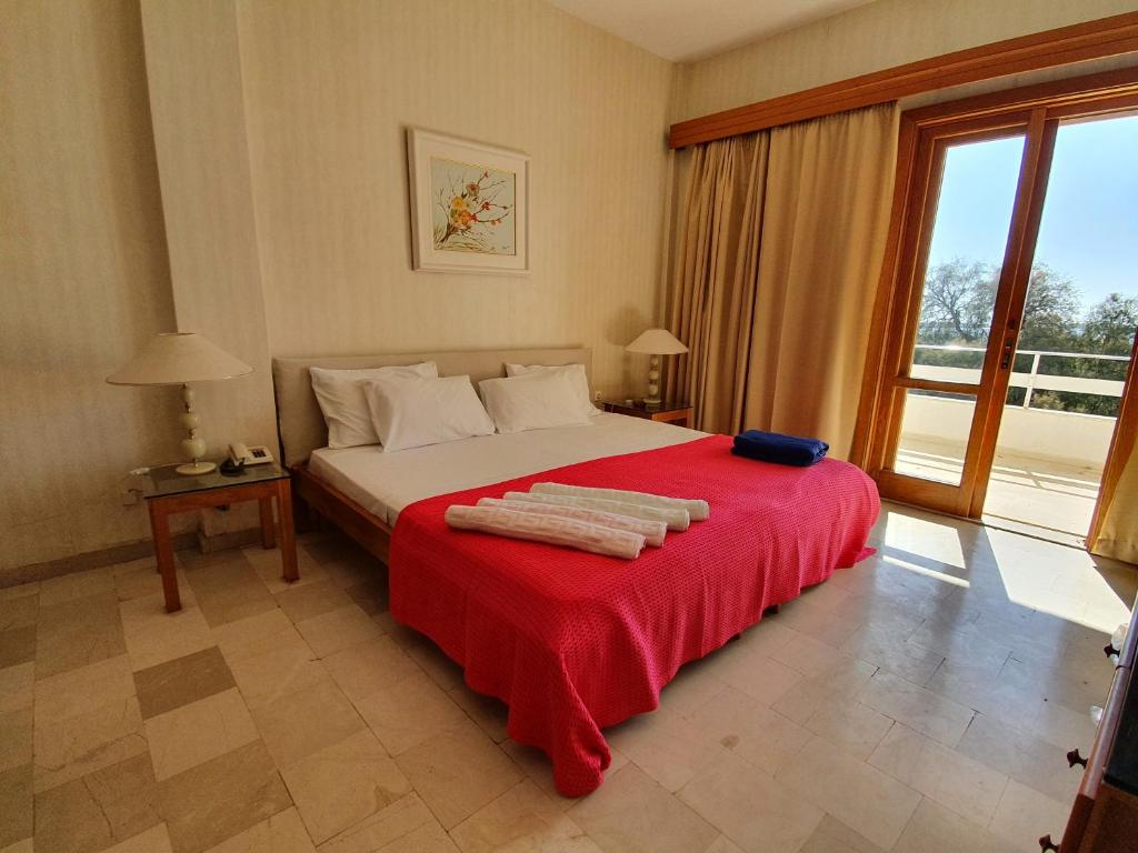 um quarto com uma cama grande e um cobertor vermelho em Hotel Elman em Palaiochora