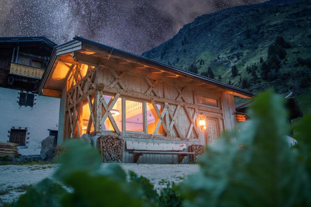 a wooden cabin with a lit up window at night at Kaser Premium Chalet am Berg in Neustift im Stubaital