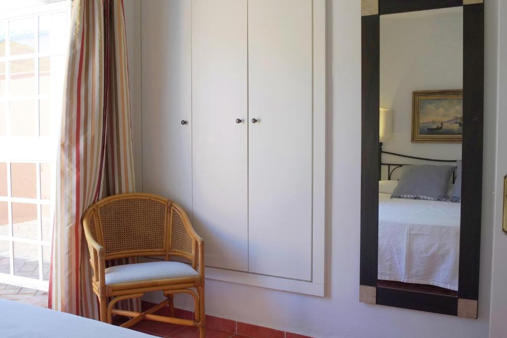 a bedroom with a mirror and a chair and a bed at Hotel Madreselva - Grupo Califa in Los Caños de Meca