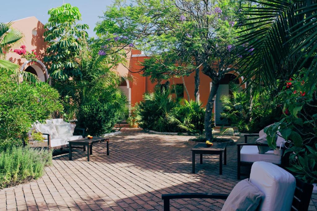 a courtyard with benches and trees and a building at Hotel Madreselva - Grupo Califa in Los Caños de Meca