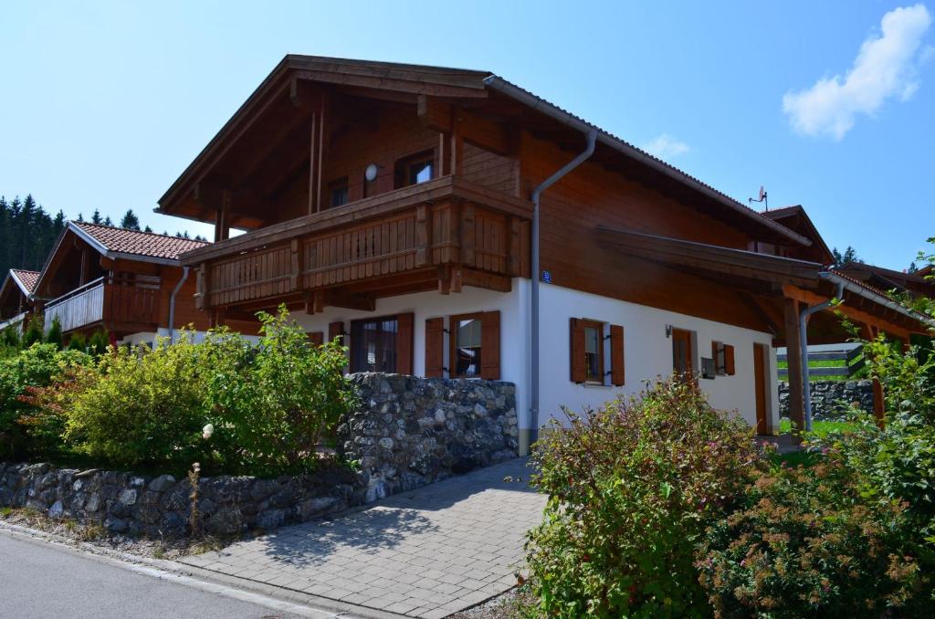 a large wooden house with a wooden roof at Feriendorf Via Claudia Haus 53 Alpenrose in Lechbruck