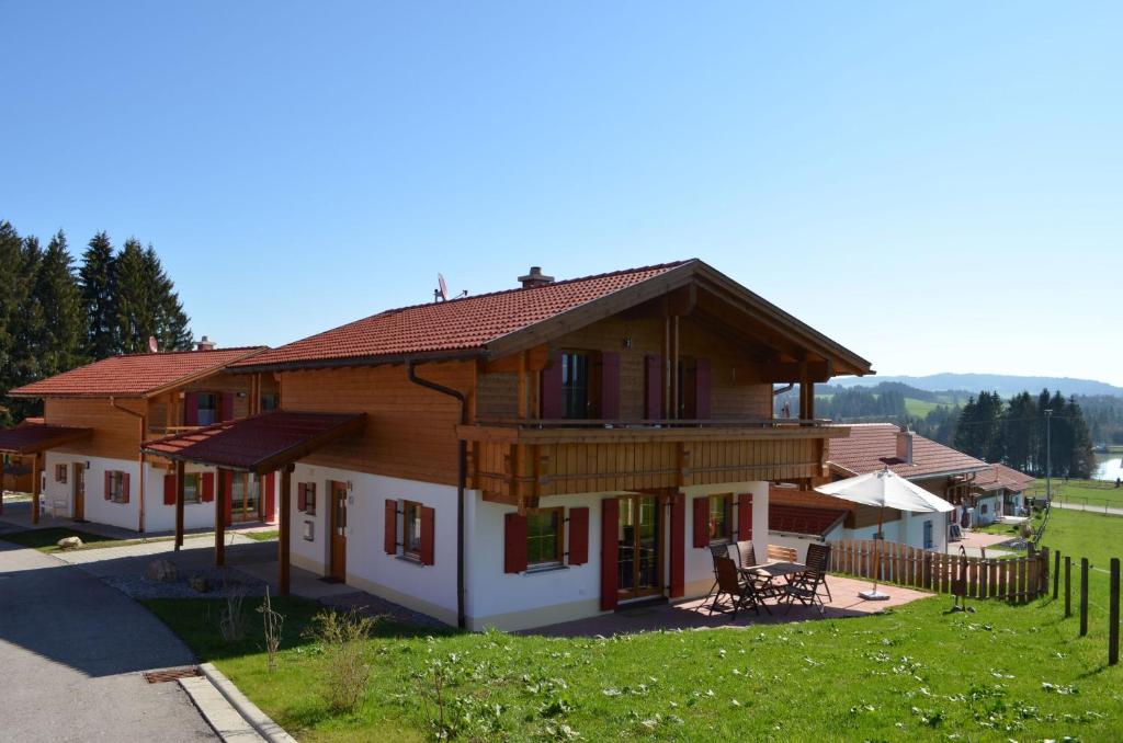 ein großes Holzhaus mit einem Tisch und Stühlen in der Unterkunft Feriendorf Via Claudia Haus 59 Gamsbock in Lechbruck