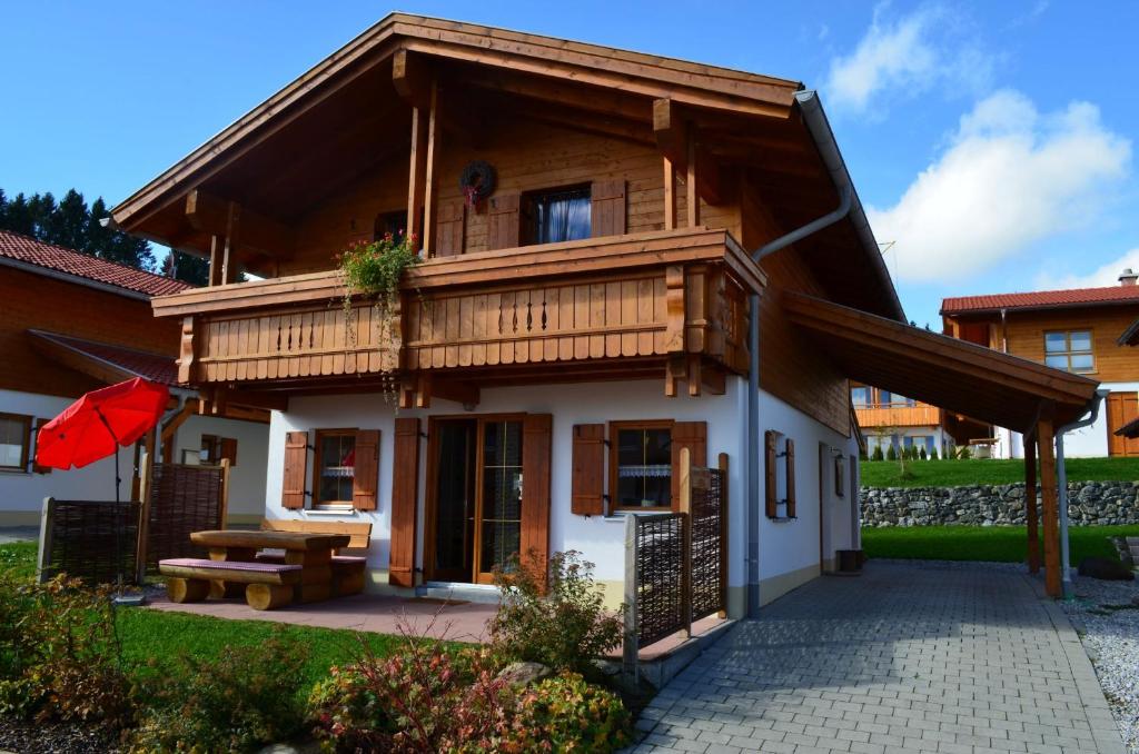 een houten huis met een balkon en een picknicktafel bij Feriendorf Via Claudia Haus 52 Bunte Kuh in Illach