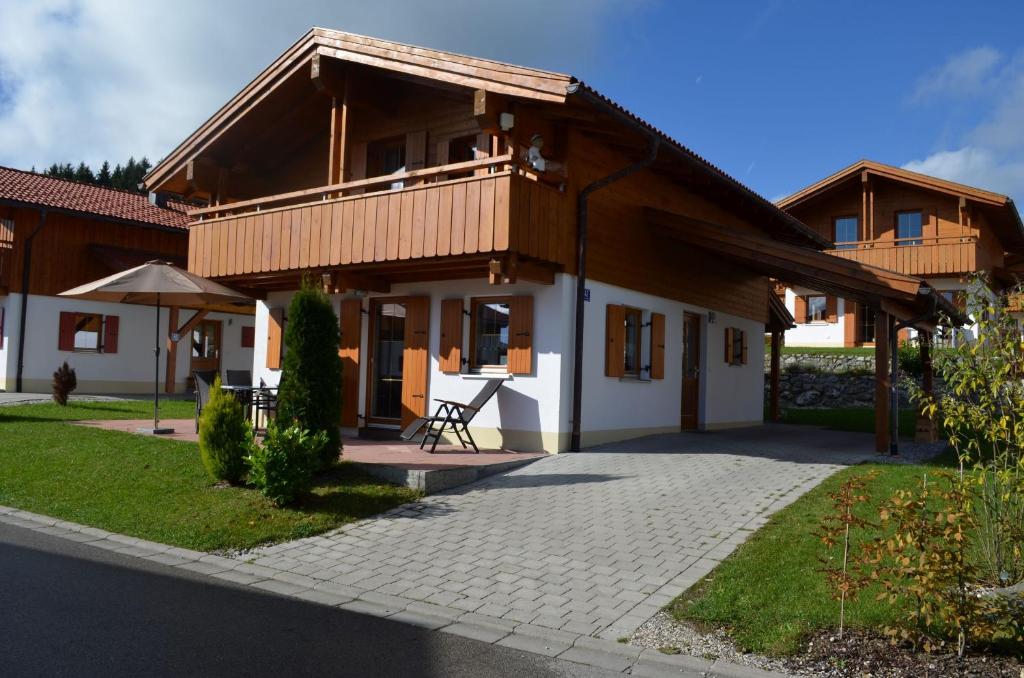 ein Haus mit einem Holzdach und einer Terrasse in der Unterkunft Feriendorf Via Claudia Haus 42 Onkel Leo in Lechbruck