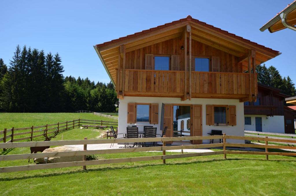 a large wooden house with a fence in a field at Feriendorf Via Claudia Haus 75 Waldromantik in Lechbruck