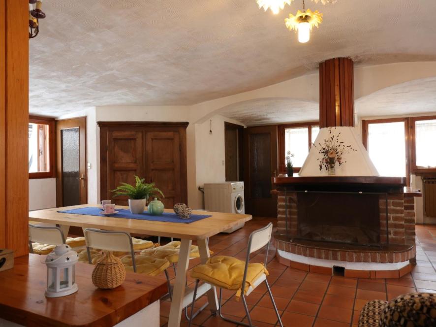 a living room with a table and a fireplace at [Ghigo di Prali] Ampio Chalet tra le Alpi in Ghigo