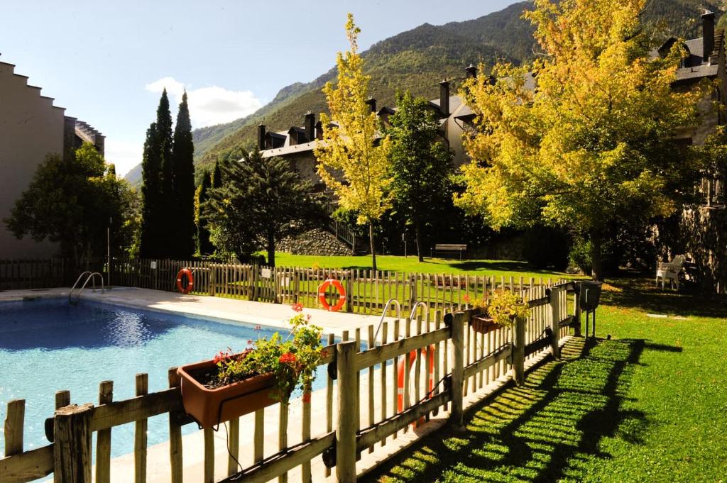 a fence around a pool with flowers in a yard at Chardín d'Alto-Apartamentos Chardins in Benasque