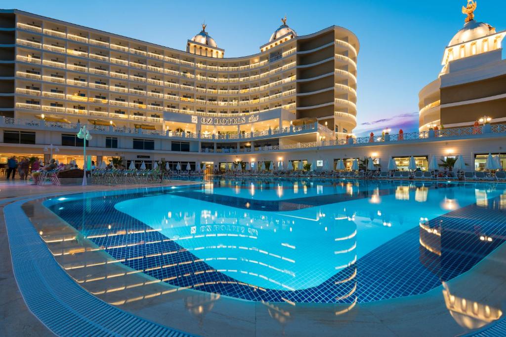 a hotel with a large swimming pool in front of a building at Oz Hotels Sui in Alanya