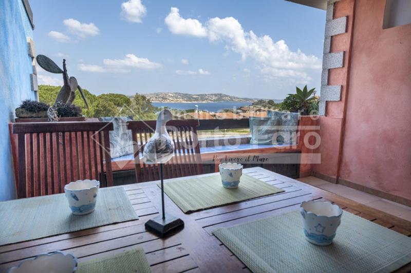 una mesa en un balcón con vistas al océano en 23 BAIA FARO - Trilocale mansardato con ampia terrazza vista mare, en Palau
