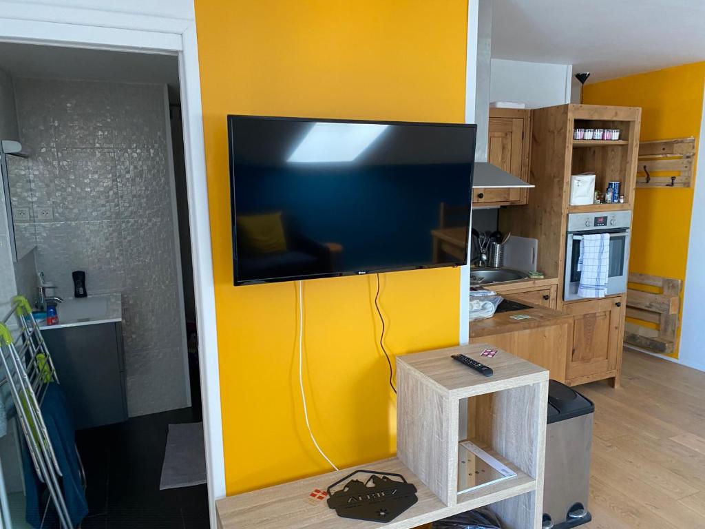 a living room with a tv on a yellow wall at Le Loire-Etain in Albiez-Montrond