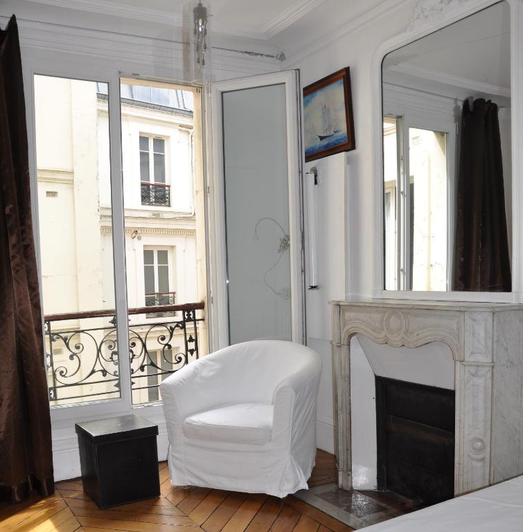 - une chaise blanche dans une chambre avec cheminée dans l'établissement Plein centre, à Paris