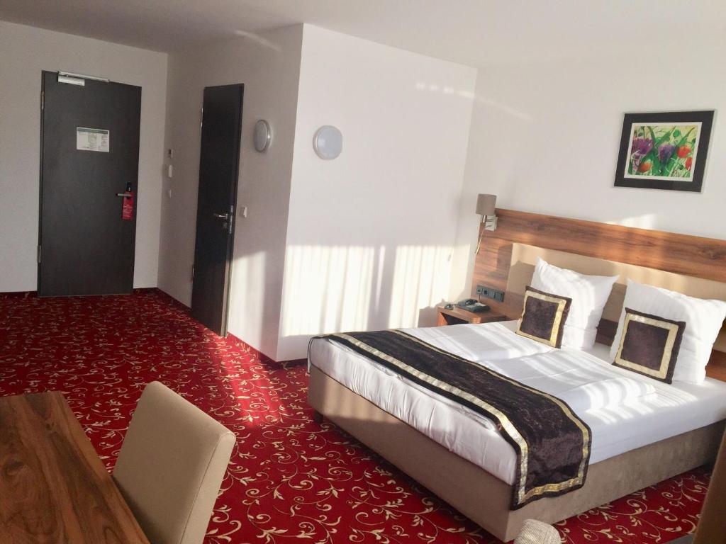 オッフェンバッハにあるHotel Lunaの赤いカーペット敷きの客室で、ベッド1台が備わります。