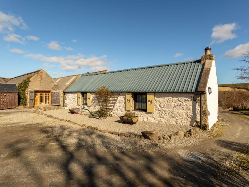a stone cottage with a green roof on a road at Holiday Home Deveron Valley Cottages by Interhome in Marnoch