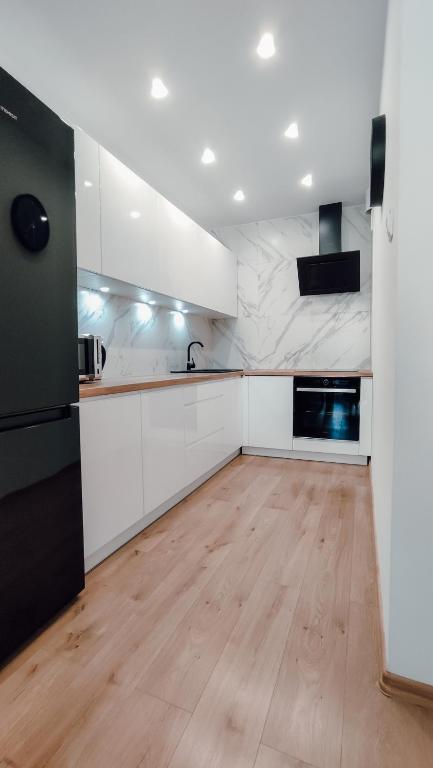 duża kuchnia z białymi szafkami i drewnianą podłogą w obiekcie Złote Apartamenty 58 w mieście Legnica