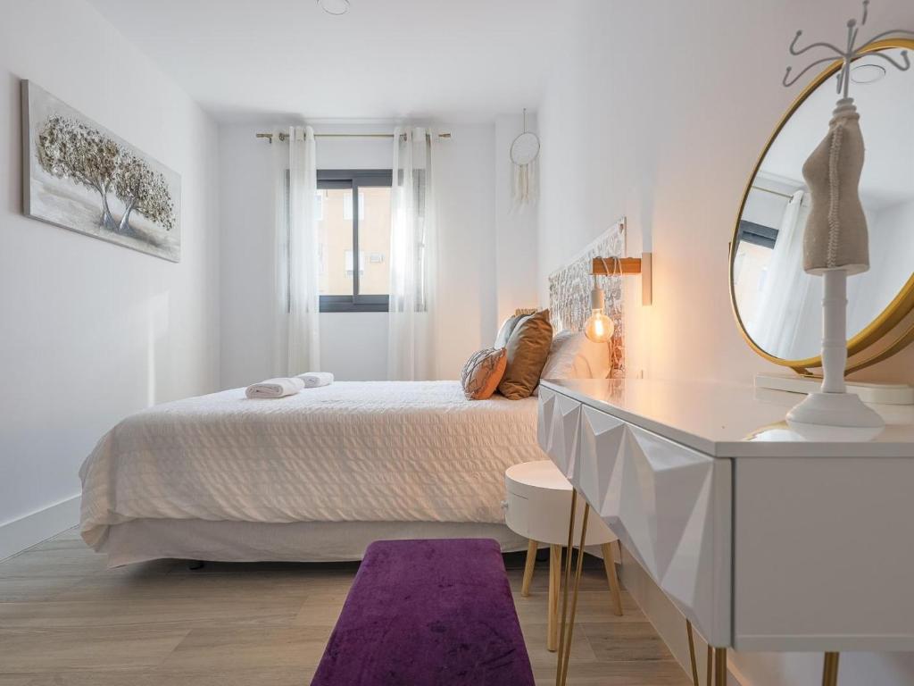 een witte slaapkamer met een bed en een spiegel bij Family HOME SUITS Encantos de Sevilla in Sevilla