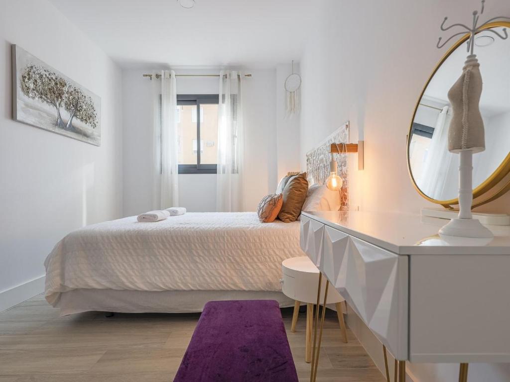 biała sypialnia z łóżkiem i lustrem w obiekcie Family HOME SUITS Encantos de Sevilla w Sewilli